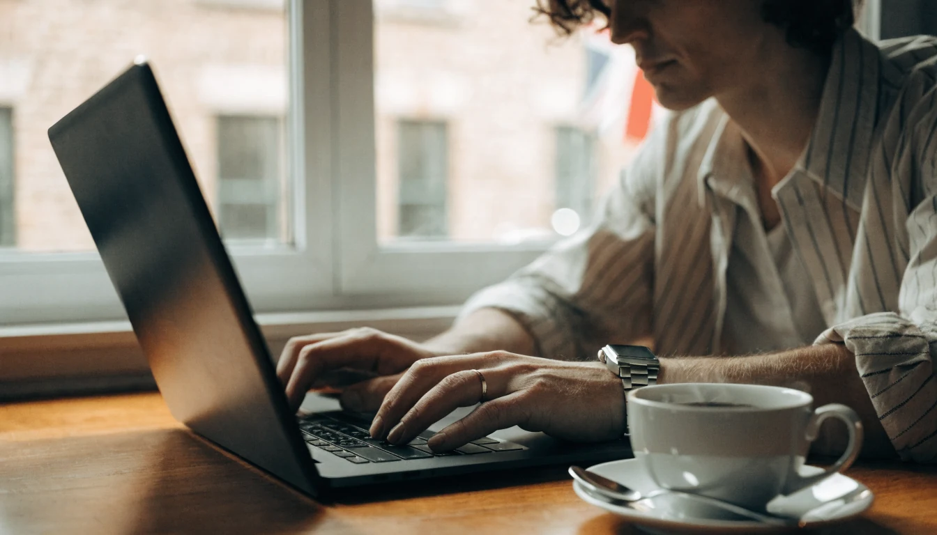 British reviewer writing at a desk with tea and laptop